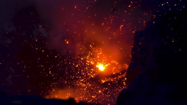 CLOSE UP: Glowing hot magma bursting out of the active volcanic crater in Vanuatu. Bright orange magma illuminates the crater of an active volcano on a remote island in the Pacific. Eruption at night.