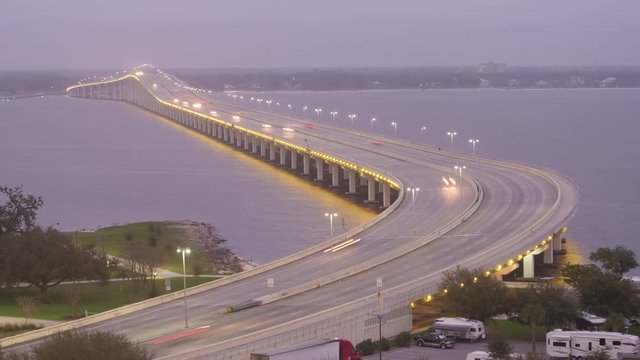 A day to night timelapse view of traffic passing over the Route 90 Biloxi Bay Bridge, newly rebuilt after Hurricane Katrina. Ocean Springs in the distance.  	