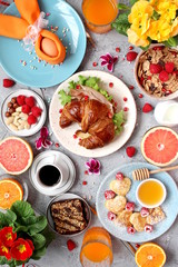 Breakfast food table. Festive brunch set, meal variety with pancakes, croissants, juice, fresh berries, granola and fresh fruits. Easter breakfast. Top view with copy space.