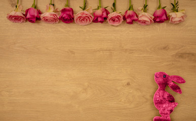 Pink easter bunny with roses on wooden background
