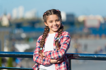 Fototapeta premium Leisure options. Free time and leisure. Girl cute kid with braids relaxing urban background defocused. Organize activities for teenagers. Vacation and leisure. What do on holidays. Sunny day walk