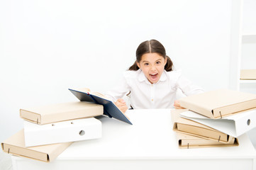 Like a fury. Angry pupil clenched her hands into fists. Little girl dont like reading lesson book in school. Small child refuses having literature lesson. Schoolgirl hates reading school book at desk