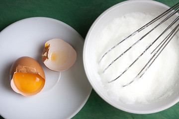 YEMA DE HUEVO CON CÁSCARAS Y BATIDORA DE METAL CON CLARA DE HUEVO A PUNTO DE NIEVE