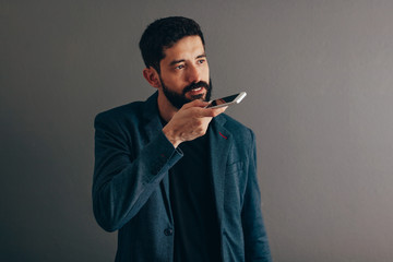 Leisure, technology, communication and people concept - businessman using voice command recorder or calling on smartphone