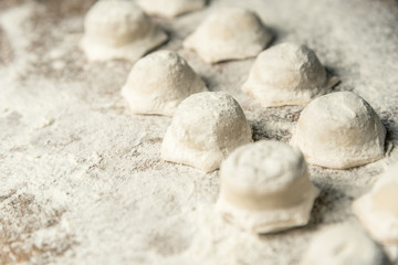 Uzbek national food Chuchvara, like dumplings, on a wooden board, in flour