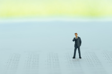 Obraz premium Miniature businessman standing on finance reports with number of buy and sale using as investment, sale business or accounting audit concept