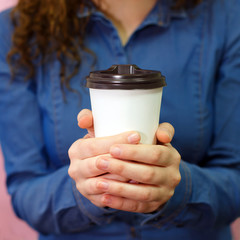 Hands young model girl in denim shirt holds paper plastic coffee glass drinking