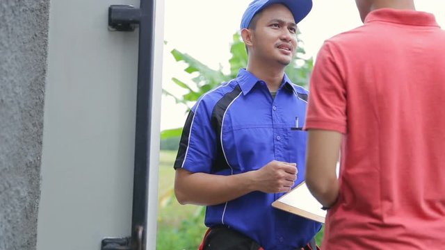 Smiling techinician in blue uniform coming to customer house
