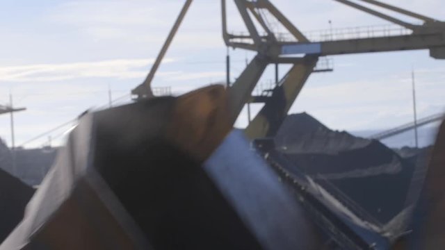 Coal stacker reclaimer bucket dumper spinning, terminal in background