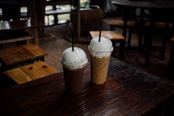 Iced cocoa and coffee in plastic served on wooden table.