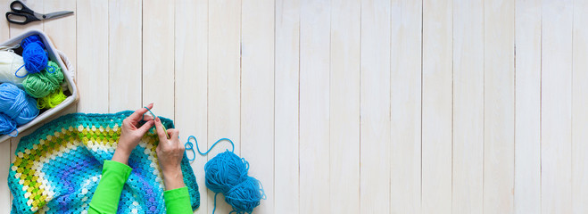 Female hands knitting with color wool, top view