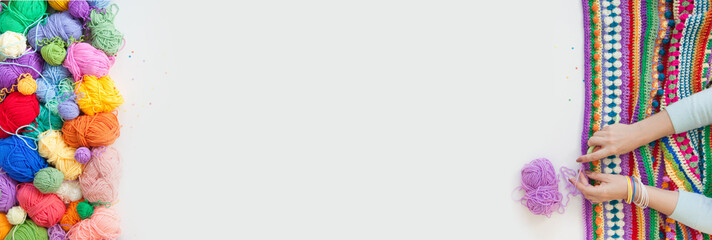 Balls of colored yarn. View from above. All the colors of the rainbow. Sample knit. Women's hands are knitted. Crochet.