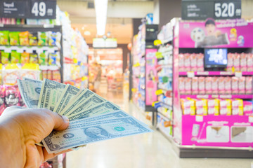 A hand holding dollars on shop. A man holding dollars for cash  on product background.Money for sales exchange. Photo concept  finances and money.