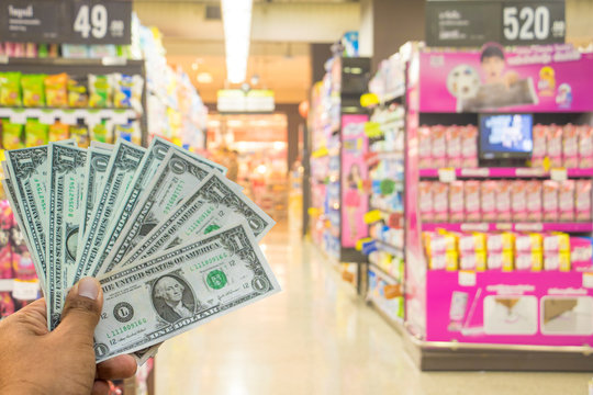 A hand holding dollars on shop. A man holding dollars for cash  on product background.Money for sales exchange. Photo concept  finances and money.