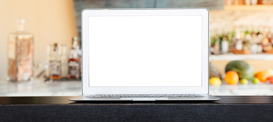 A computer laptop with white blank space for text or montage product display on the bar counter...