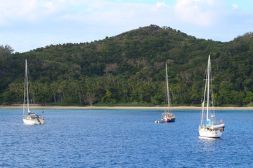 Fototapeta na wymiar Sailboats anchored in a bay of the Sacred Islands, Mamanuca Islands, Fiji