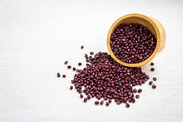 Small organic red beans in round wooden bowl on canvas fabric background, vegetarian food
