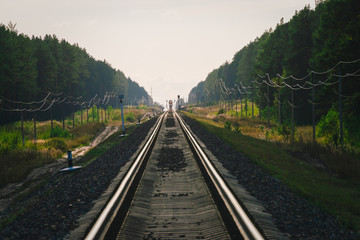 Mystic train travels by rail along forest. Railway traffic light and locomotive on railroad in distance. Mirage on railway track. Atmospheric landscape.