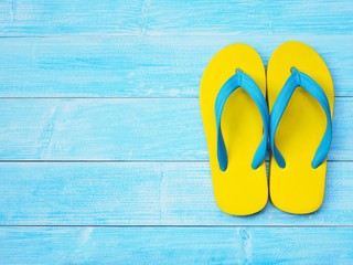 yellow flip flop shoes on blue wooden background - obrazy, fototapety, plakaty