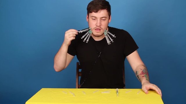 The guy punctures his cheeks with syringes. emotional portrait of a crazy guy in close-up. concept: the nervous breakdown, mental disease, headaches and migraine.