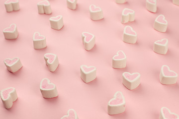 Tasty heart shaped pink marshmallows on color pink background, pattern, monochrome sweetness background, copy space