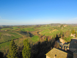 Winter tuscany hills landscape with green fields and blue sky from tower of medieval town Certaldo