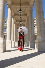 Femme avec ombrelle blanche en dentelle sous un portique du palais royal