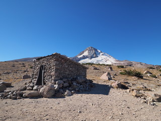 The Cooper Spur shelter on the Timberline Trail with Mount Hood and the Eliot Glacier in the background.