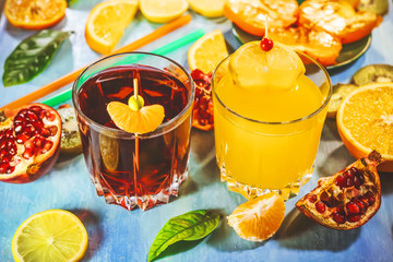 Pomegranate juice and orange juice. sliced ​​citrus fruits on a blue painted board. orange, kiwi, pomegranate, persimmon, mandarin. with fruit sticks.