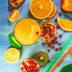 orange juice. sliced ​​citrus fruits on a blue painted board. orange, kiwi, pomegranate, persimmon, mandarin. with fruit sticks.