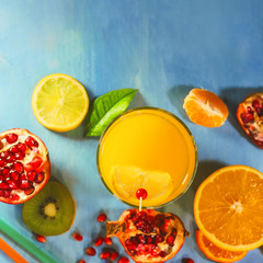 orange juice. sliced ​​citrus fruits on a blue painted board. orange, kiwi, pomegranate, persimmon, mandarin. with fruit sticks.