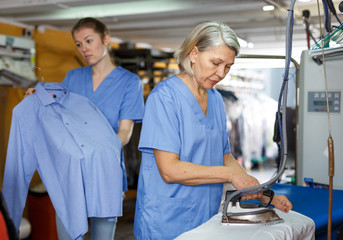 Obraz premium Workers ironing clothes after cleaning