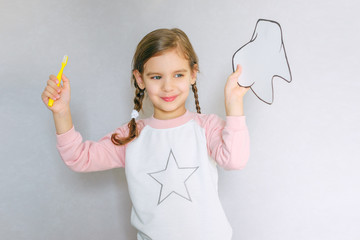 Cute girl holding toothbrush and tooth layout. Oral hygiene. Pediatric dentistry.