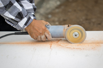 Image of worker using tool to cut white tile.