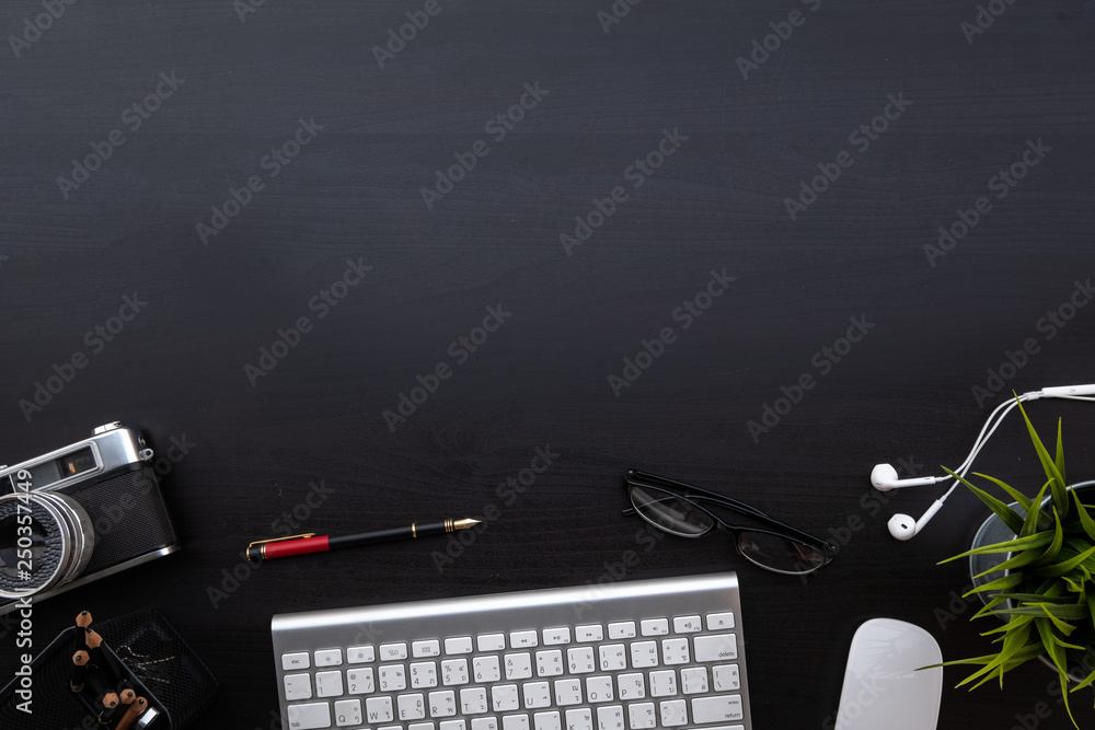 Poster flat lay of top view modern black wood desk work table with computer laptop and retro film camera in