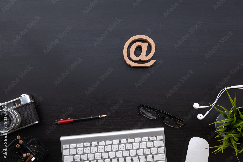 Poster flat lay of top view modern black wood desk work table with computer laptop and retro film camera of