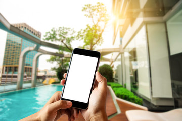 Hand holding white mobile phone with blank white screen  in pool.