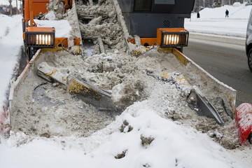 Harvester snow plow cleans the snow from the roadway. Collected snow on the conveyor is dumped into...