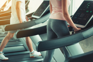 Fototapeta na wymiar Portrait of Couple Love is Workout in Fitness Gym Together. Attractive Woman is Working Out Jogging on Treadmill Machine With Her Exercise Trainer., Sport Club and Healthy Concept.
