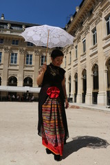 Femme avec ombrelle blanche marchant dans la cour du palais royal à Paris