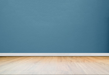 Blue concrete wall in empty room with wooden floor.