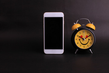 Blank smartphone and clock on black background