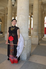 Femme avec ombrelle blanche adevant une colonne du palais royal à Paris