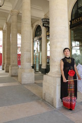 Femme avec ombrelle blanche appuyée sur une colonne du palais royal à Paris