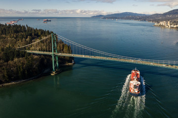 Aerial view of a cargo ship sailing underneath lions gate bridge in Vancouver, Canada