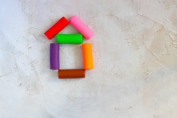 Colorful clay plasticine, modelling clay placed like house on cement background, horizontal, education, child psychology, neuropsychology fine motor skills manual dexterity copy space estate realty