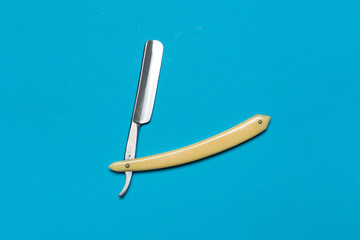 Very old rusty classic straight razor lying on blue background