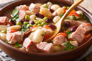 Homemade slow kidney bean soup with ham, tomatoes and herbs close-up in a bowl. horizontal