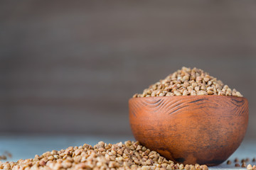 Dry buckwheat in brown clay bowl on wooden table. gluten free grain for healthy diet