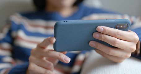 Woman watch on cellphone and sit on sofa at home